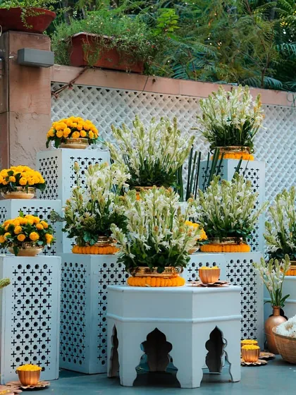 A beautiful installation of yellow marigolds and white tuberoses, arranged on modern white stands. This is a fresh take on traditional Haldi decor.