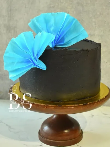 A stunning black ganache cake with vibrant blue wafer paper accents, created by a student during Week 3 of my baking masterclass.