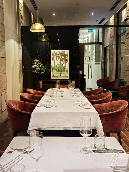 A long table set for a group, with plush velvet chairs and elegant pendant lighting. We can accommodate both intimate dinners and larger celebrations.