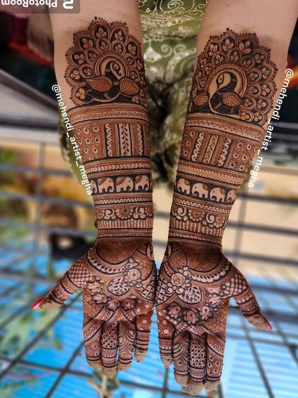 A powerful and traditional design with bold peacock motifs at the top of the arms. The design includes bands of elephants and intricate floral work on the palms, perfect for a classic bridal look.