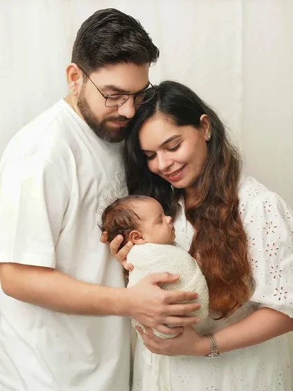 A family portrait where the parents are looking down at their newborn with adoration. This pose naturally creates a story of love and focus on the new baby.