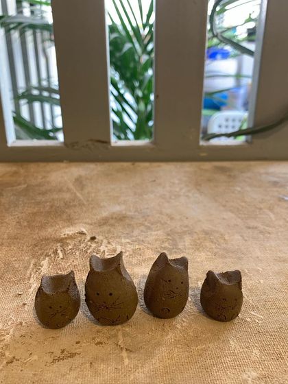 A family of four tiny clay owls, hand-built by a group of friends during a workshop.