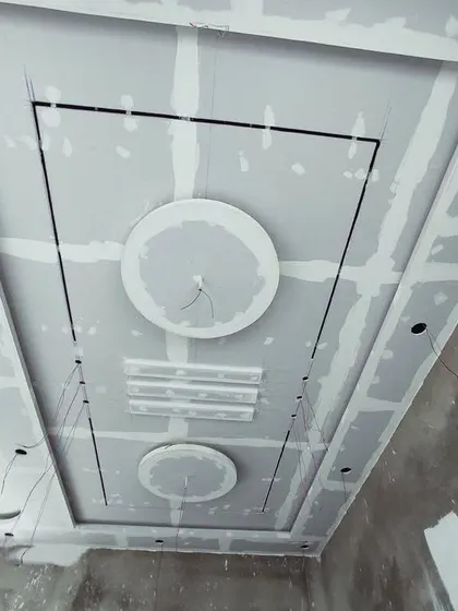 A modern ceiling layout with circular and rectangular elements, seen here before the final plastering. The black lines are guides for installing profile lights.