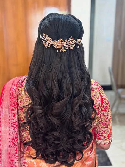 A romantic half-up hairstyle with voluminous, well defined curls. The look is completed with an elegant, leaf motif hair accessory that adds a touch of sparkle without overpowering the style.