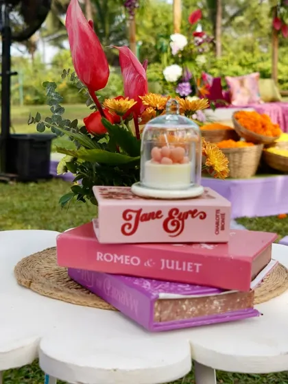 Another angle of the quirky centerpiece, showing the stack of romantic novels and a candle under a cloche.