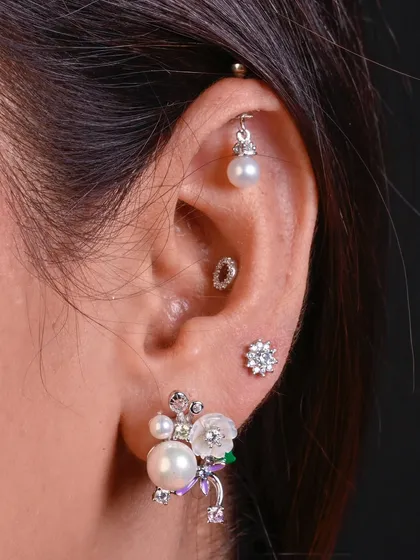 A beautiful combination of classic and contemporary styles. This ear features a pearl drop hanging, an elegant pearl cluster stud, and other delicate silver pieces for a timeless look.