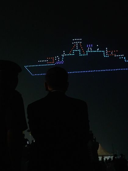 Silhouetted figures watch as our drones form a warship during the Navy Day celebrations. Our shows create powerful, shared moments of reflection and respect for our armed forces.