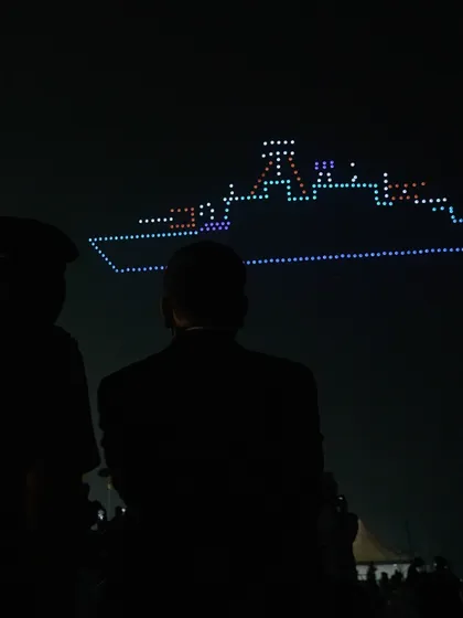 Silhouetted figures watch as our drones form a warship during the Navy Day celebrations. Our shows create powerful, shared moments of reflection and respect for our armed forces.