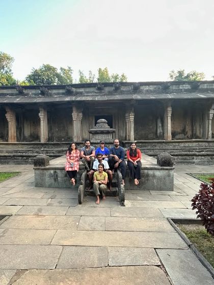 A group sitting on an old cannon in front of a historic temple, a unique photo opportunity.