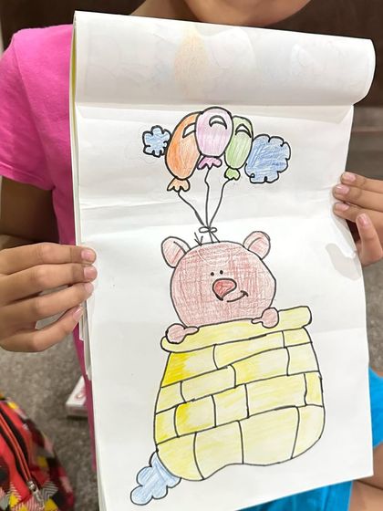 A bear flying with balloons. This imaginative piece shows how we encourage storytelling through art in our classes.