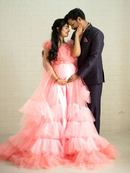 An intimate and loving pose that beautifully captures the connection between the expecting parents. The soft tulle of the pink gown adds to the romantic atmosphere.