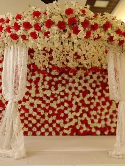This Navratri or Ganpati decor combines a wall of red and white flowers with delicate lace drapes for a look that is both bold and soft.