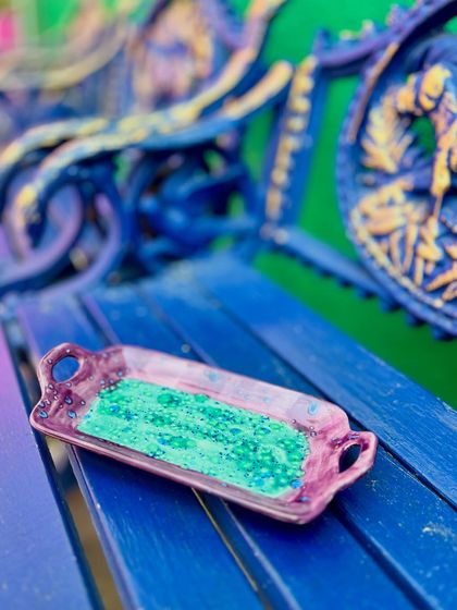 A handled tray from the Kaleidoscope Collection, showcasing a rich purple and a crackled green interior. I love experimenting with how different pop colors and textures interact in the kiln.