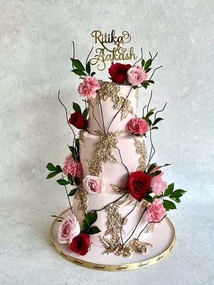 I love playing with textures and florals. This three-tiered engagement cake features delicate gold stenciling over a soft pink fondant, with beautiful branches of red and pink sugar flowers climbing up the side.