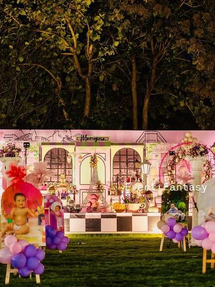 A wide view of the Parisian party setup at night, showing the beautiful photo displays and the main stage glowing with warm lights.