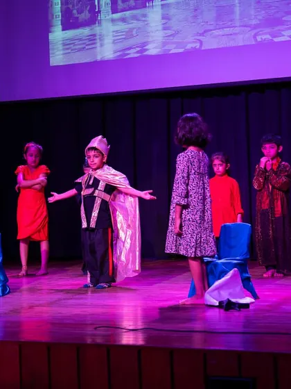 The full cast on stage for 'The Emperor's New Clothes'. This wide shot shows the use of stage space and the dynamic arrangement of actors during a scene.
