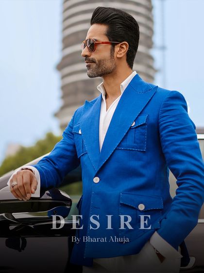 A side profile of the vibrant blue summer blazer, showcasing its sharp cut and tailored fit against a luxury vehicle. This is power dressing for the modern man.