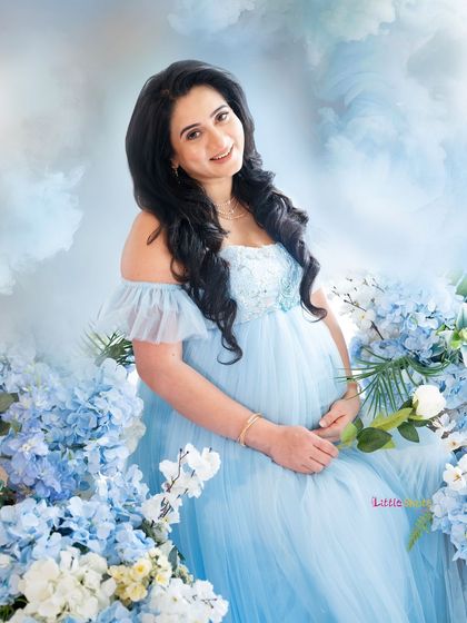 A happy, smiling portrait of the mom-to-be, surrounded by beautiful blue flowers.
