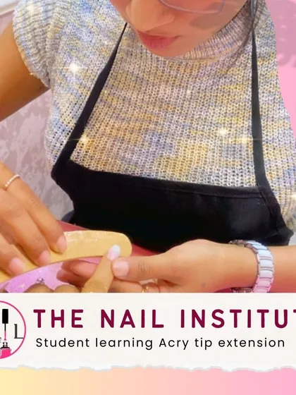 A student carefully files the side walls of an acry-tip extension to create a clean and slender nail shape.