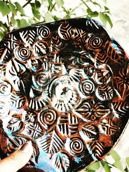 Another beautiful example of a hand-built platter with intricate stamped patterns, enhanced by the dark, rich finish from the firing process.
