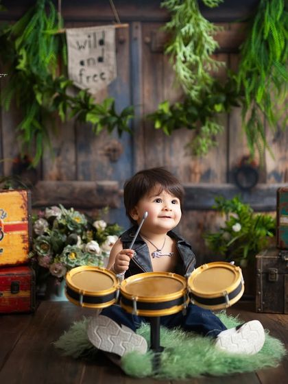 A little drummer boy in our rustic biker setup. The combination of musical instruments and vintage props creates a rich, textured backdrop.