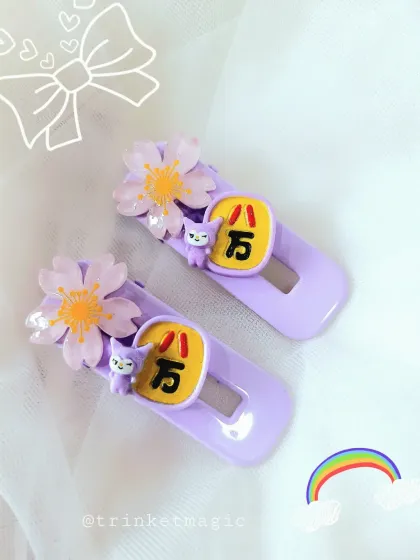 These purple hair clips have a Japanese-inspired theme, with cherry blossoms and a cute character charm.