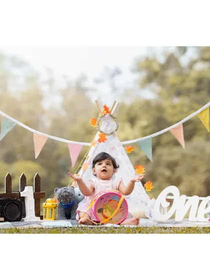 Reaching for the sky during her first birthday celebration. This wide shot of Anwita's themed setup captures her playful energy and the scale of the beautiful outdoor scene we created.