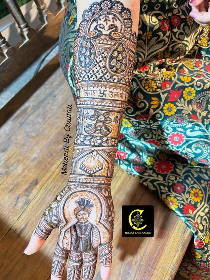 A side view of a groom's portrait on the bride's arm. The design includes peacocks and auspicious symbols, all drawn with fine lines and careful shading to bring the artwork to life.