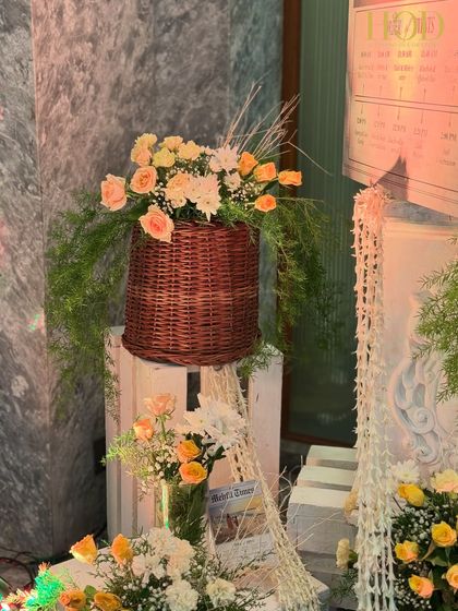 Another detail of the rustic welcome corner, showing the beautiful textures of the wicker baskets, flowers, and white wooden crates.
