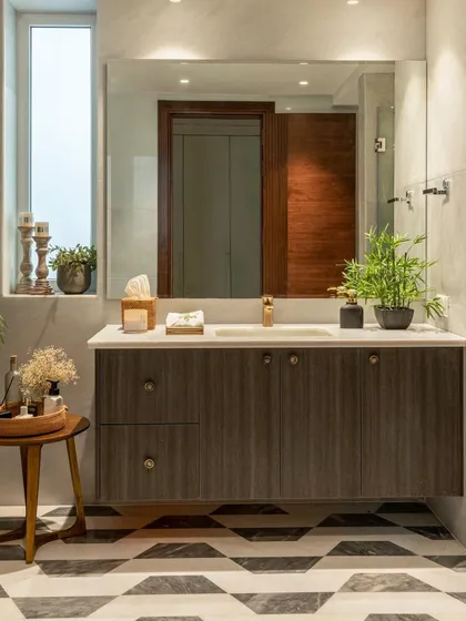 A dark wood floating vanity is paired with geometric black-and-white floor tiles in this bathroom. The large mirror and ample counter space make it as functional as it is stylish.