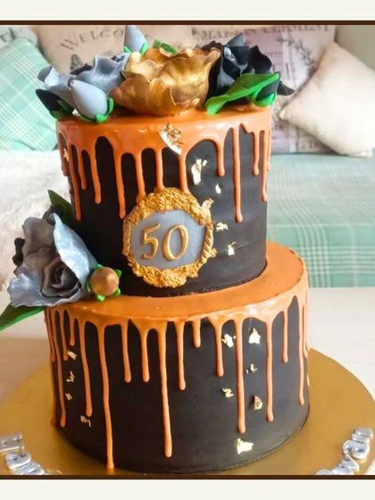 A bold and striking two-tier cake in black and orange with a drip effect, perfect for a 50th birthday.