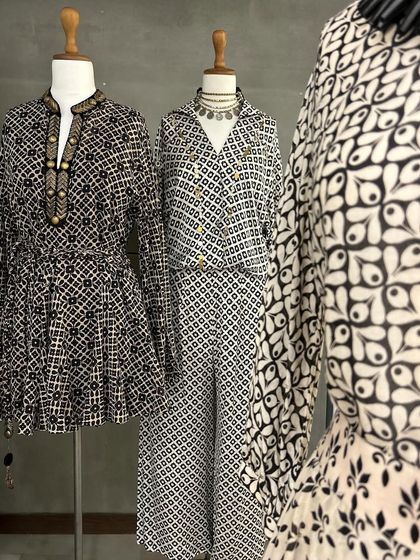 A collection of classic black and white printed outfits, featuring a peplum top, a jumpsuit, and a dress, all with modern silhouettes.