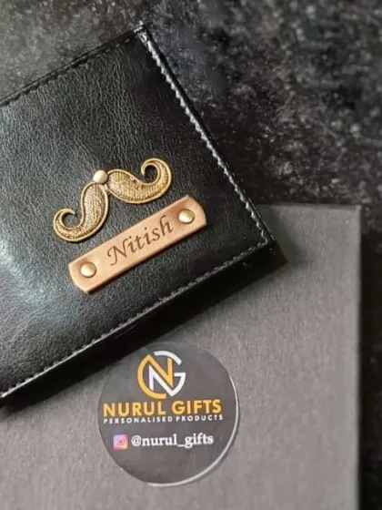 A classic black personalized wallet with a mustache charm and the name 'Nitish', presented in its elegant gift box.