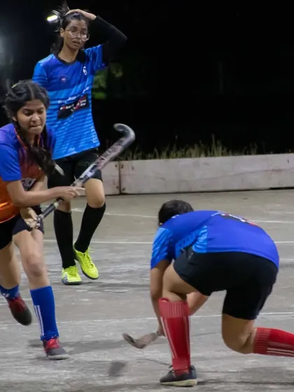 A player executes a reverse-stick shot under pressure from a defender. We teach advanced skills to all our players, ensuring they have a complete technical toolkit.
