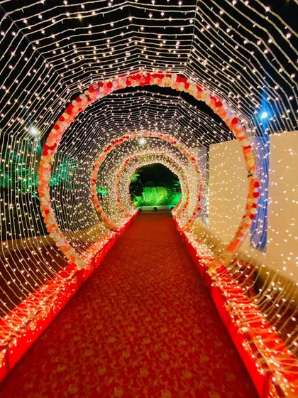 A tunnel of light to welcome your guests. I created this enchanting walkway using circular arches wrapped in flowers and thousands of twinkling fairy lights for a magical nighttime entrance.
