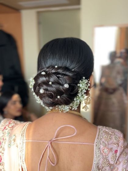 A beautiful and intricate low bun, decorated with baby's breath and pearls, a very popular and romantic choice for receptions.