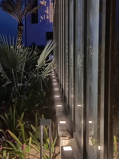 A detail shot from the Zirakpur office, showing the ground-level uplighting along the glass wall. This technique, known as wall grazing, adds texture and rhythm while illuminating the surrounding landscape elements.