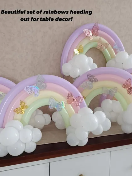 A beautiful set of pastel rainbow balloon sculptures with butterfly accents, ready to be used as table centerpieces for a whimsical party.