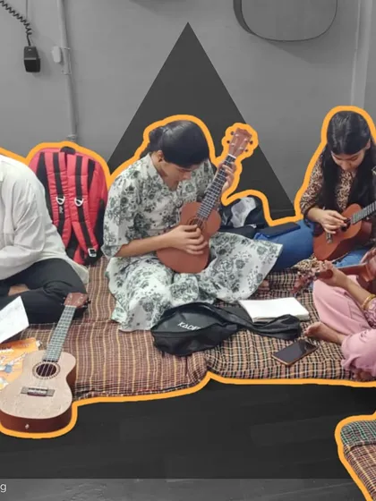 A student diligently takes notes while her friends practice the ukulele beside her. Our classes combine practical playing with music theory to provide a well-rounded education.