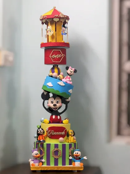The full 5-tier Mickey Mouse topsy-turvy cake, featuring a rotating carousel on top and a gravity-defying tier held up by Mickey himself.