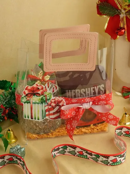 A cute and compact Christmas gift bag. This clear bag with pink handles is filled with Hershey's Kisses and other small treats, tied with a festive ribbon.