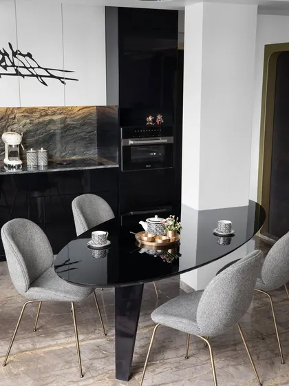 This compact yet sensational kitchen and dining space features a uniquely crafted oval table that emerges from an architectural cocoon, inviting moments of togetherness.