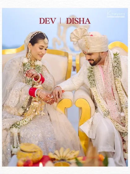 A beautiful portrait of the couple during their wedding ceremony, seated together as they begin their new life. Their coordinated white outfits add to the elegance of the moment.