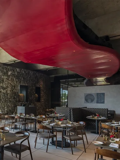 A dramatic, curving red ceiling feature flows through the restaurant at the Radisson Resort, contrasting with the rugged stone walls and adding a sculptural, artistic element to the space.