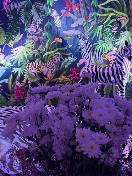 A wide view of the jungle-themed photo area, showing the zebra-print floor, the vibrant wallpaper, and the life-sized animal statues. The entire setup is designed to be a fun and immersive photo opportunity.