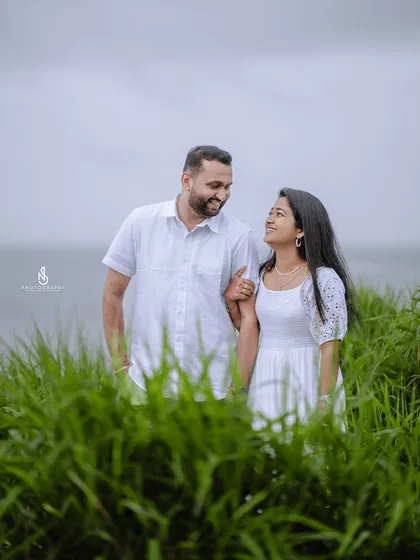 A gentle walk, arm-in-arm, with the sea providing a serene background. This is a simple yet elegant pose for any couple.
