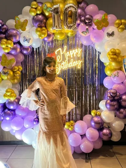The birthday girl posing in front of her beautiful butterfly-themed backdrop.