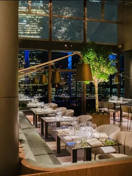 Another view of the One40 Rooftop interior, highlighting the balance between cozy dining nooks and the expansive urban landscape visible through the large windows.