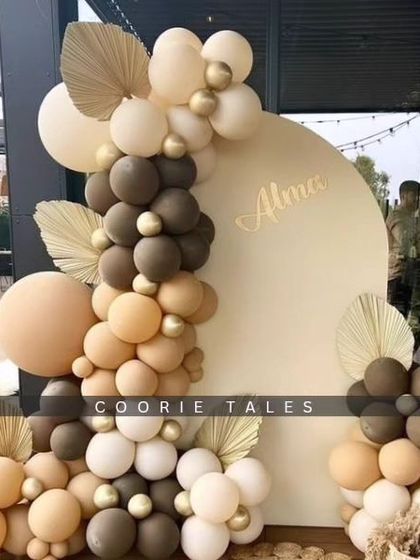 A beautiful example of our minimalist boho aesthetic. This outdoor setup uses a simple arched backdrop and a tastefully arranged balloon garland in neutral tones, accented with dried palm leaves for a touch of texture.