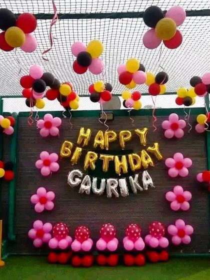 A simple and colorful outdoor birthday decoration on a terrace, with personalized name balloons and flower-shaped balloon clusters.